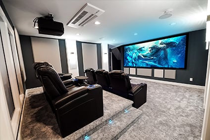 7.4.4 home theater with two rows of Audio Advice revolutions with Kong vs Godzilla playing on the screen